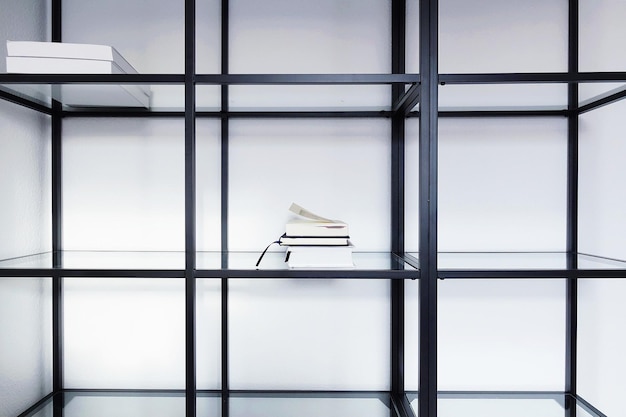 Photo stacked books on shelf by white wall