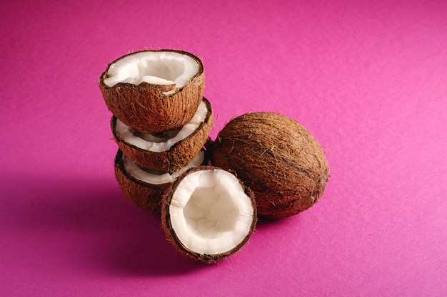 Frutti impilati della noce di cocco sul concetto tropicale dell'alimento dell'estratto della superficie della pianura porpora rosa