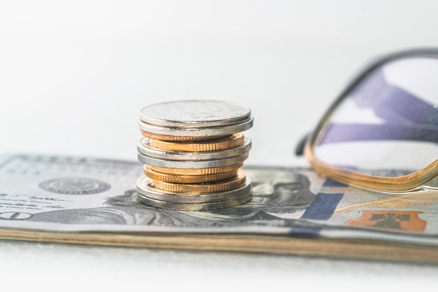 Stacked coins along with bank cards and credit cards are laid on top of the spread of dollars