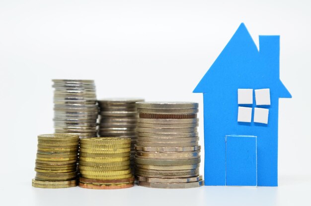 Photo stacked coins with model house over white background