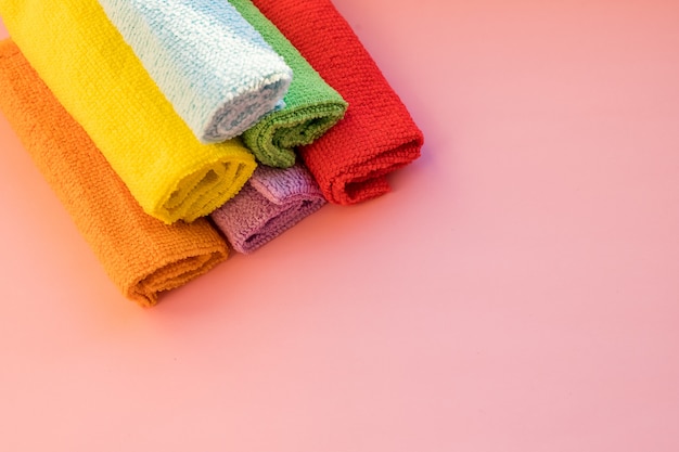 Stacked colorful microfiber cleaning cloths on a pink background. dry microfiber cloths for different surfaces cleaning in kitchen. Copy space for text or logo.