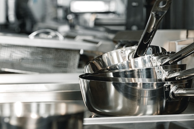 Stacked industrial metal cooking pots on proffesional kitchen