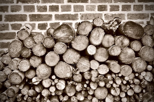 Photo stacked logs against brick wall