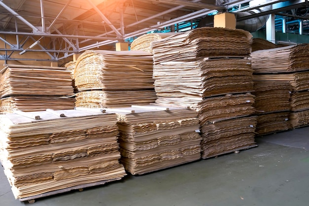 Stacked plywood and wooden board products against defocused blurred piece of industrial warehouse storage on production site Copy space Selective focus