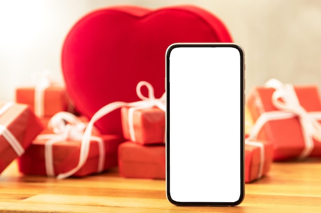 Stacked red gift boxes and heart shaped box on background and smartphone with screen mockup