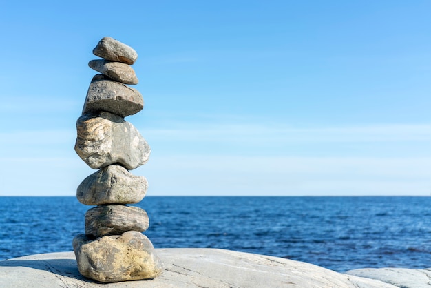 Stacked Rocks balancing, stacking with precision. Stone tower on the shore. Copy space.