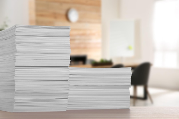 Stacked sheets of paper on wooden table in office space for text