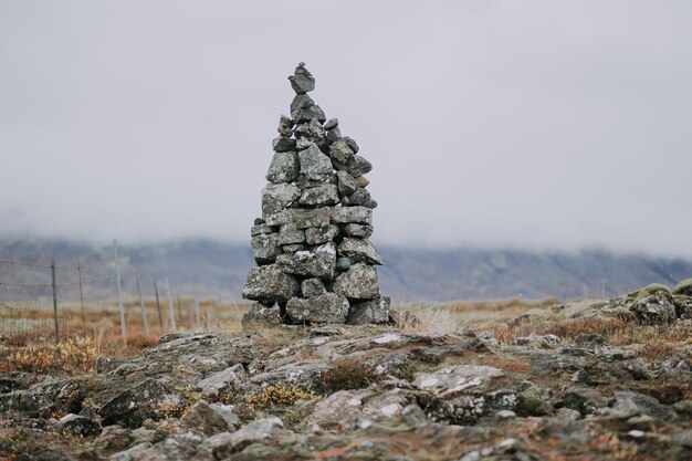 Stacked stones on field against sky