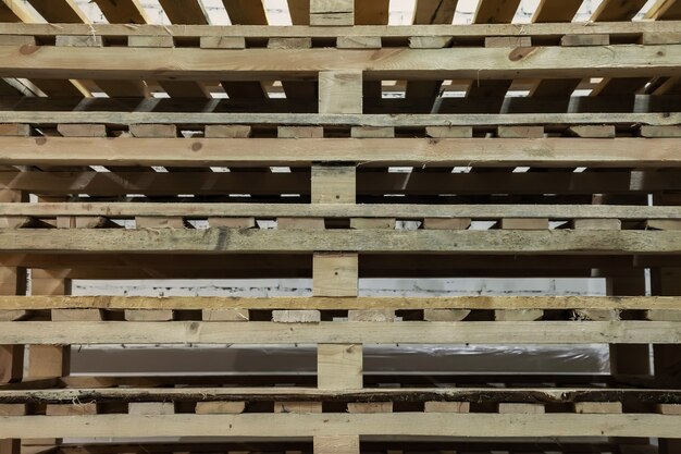 Stacked used wooden pallets in warehouse. Stacks of Euro-type cargo pallets. Background of wooden pallets. Concept of warehousing and storage of goods