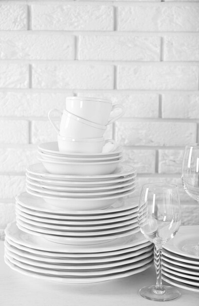 Photo stacked white clean plates glasses and cups on white table