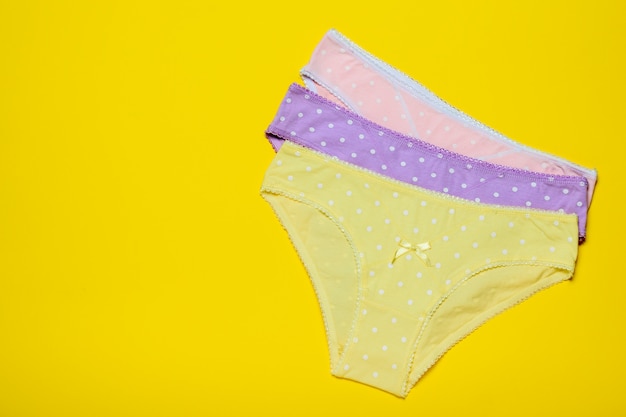 Stacked women's panties on a yellow background. Fashionable concept. Beautiful lingerie. Fashionable concept. Beautiful lingerie. Flat lay.