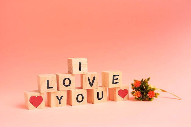 Stacked wooden blocks forming the word I love you, and a bouquet of flowers as a symbol of love and valentine's day.