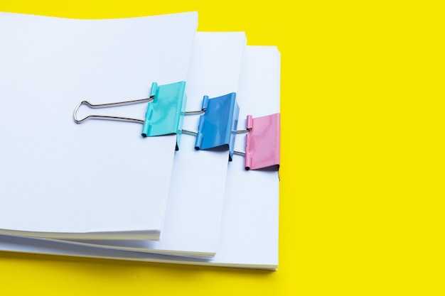 Foto impilamento di documenti aziendali con clip raccoglitore colorate su giallo