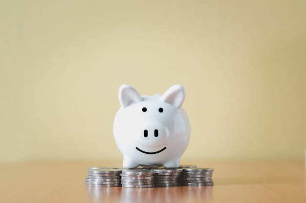 Photo stacking coins pile and white piggy bank for savings with money and planning step up to growing, saving money for retirement fund and the future plan concept.