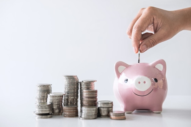 Photo stacking pile and hand putting coin into piggy bank for planning step up to growing