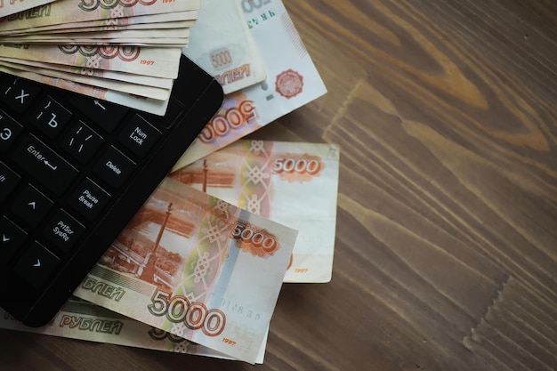 Stacks of 5000 ruble banknotes on the table next to the laptop Savings and investments in the conditions of sanctions and inflation