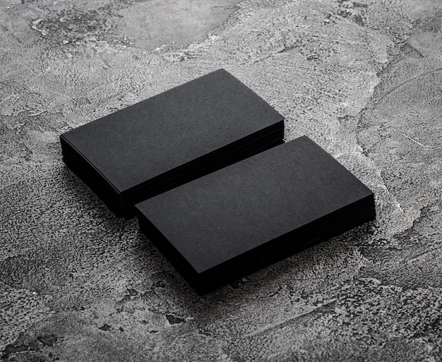 Stacks of black blank business cards on textured background