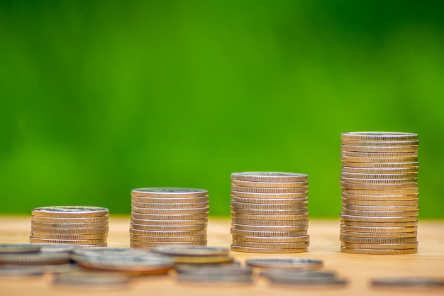 stacks of coin on wooden desk with green background concept saving money