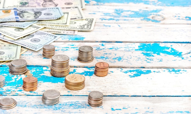 Stacks of coins and heap of US dollar bills on the old wooden table. Business background.