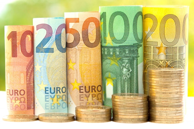 Pile di monete e banconote in euro arrotolate