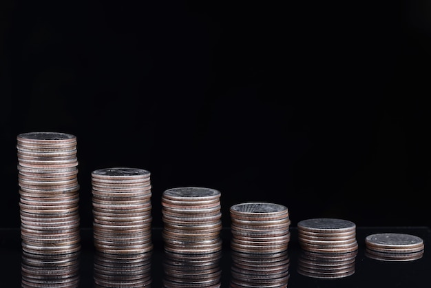 Stacks of coins worth going down on black background