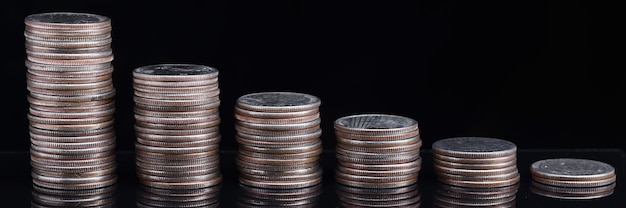 Stacks of coins worth going down on black background