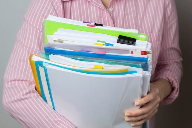 Stacks of documents in paper files in hands, business report documents. 