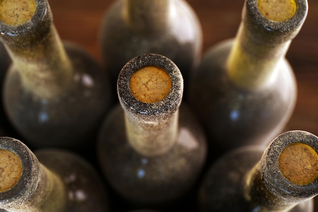 Stacks of dusty wine bottles on wooden background upside view Close up