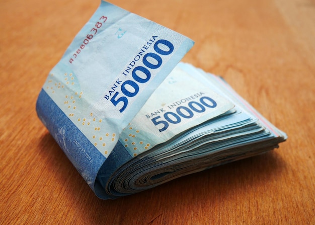 Stacks of fifty thousand rupiah banknotes on a wooden desk bag