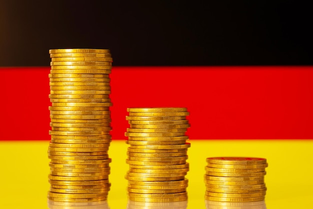 Stacks of gold coins in front of flag of Germany symbolizing crisis in economy of the country Regression of the economy concept