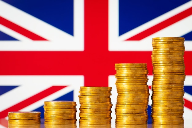 Stacks of gold coins in front of Great Britain flag Financial development of Great Britain