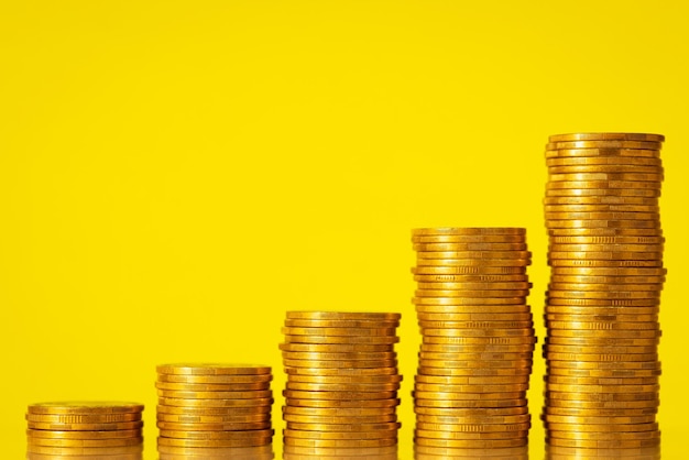 Stacks of golden coins on the yellow background Concept of rise of economic development of business income positive statistics