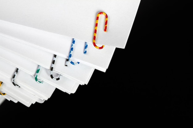 Stacks of papers with multicolored paper clips on a dark background