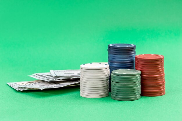 Photo stacks of poker chips with heap of money on the green background