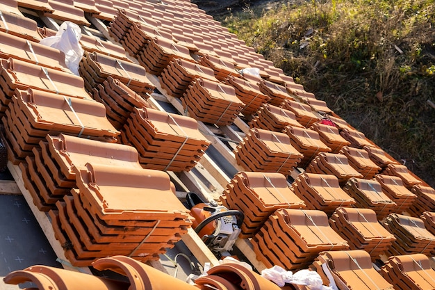 Stacks of yellow ceramic roofing tiles for covering residential building roof under construction.