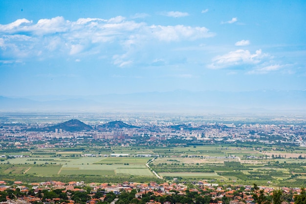 Stad Plovdiv met huizen en velden tegen de achtergrond van Rodopegebergte en heuvels bedekt met bossen en bewolkte lucht