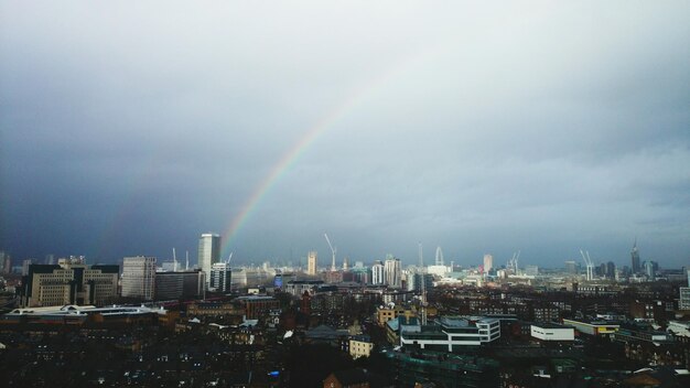 Foto stad tegen regenboog met bewolkte lucht