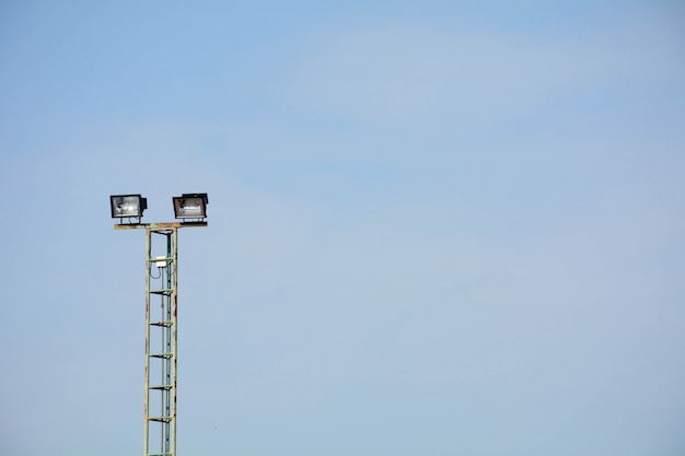 Stadionlichten bij tennisbaan op blauwe hemelachtergrond