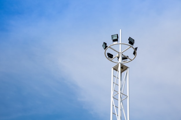 Stadium light with pole on blue sky background