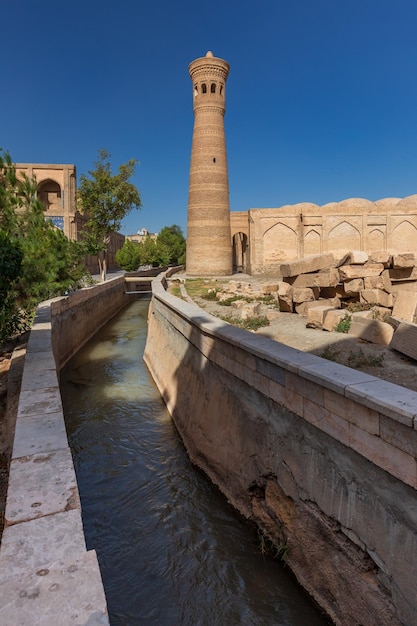 Stadsgezicht van oude oosterse stad met waterkanaalmoskee en minaret Bukhara Oezbekistan