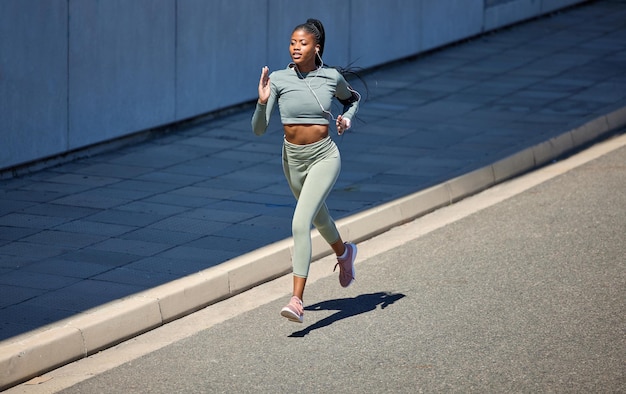 Stadsstraat fitness en lopende vrouw met oortelefoons luisterend naar muziek of motivatie audio voor gezondheidstraining met outdoor mockup Zwarte vrouw joggen of trainen met een wellness-podcast