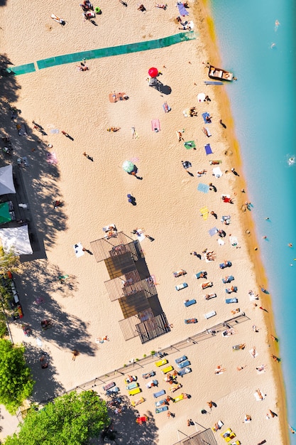 Stadsstrand met schoon azuurblauw water en veel toeristen liggend op het warme zand - bovenaanzicht geschoten met een drone