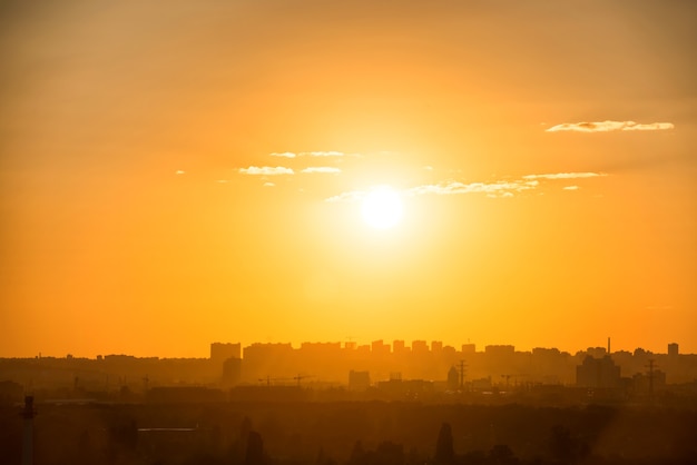 Stadszonsondergang met gebouwensilhouet op oranje horizon