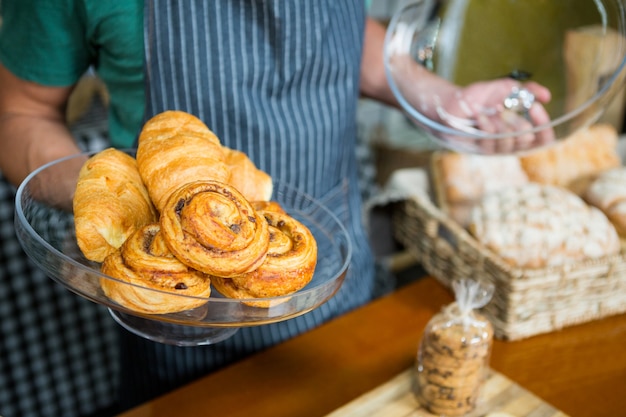 Staff holding tray of croissant at counter