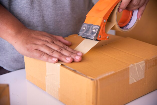 Photo staff is using the tape to pack the package goods to the customer.