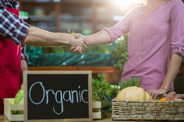 Staff shaking hand with woman in organic section