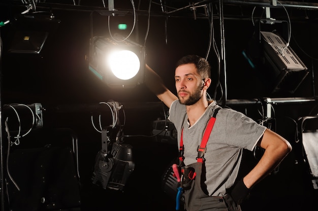 Foto l'operaio teatrale imposta le luci. l'ingegnere dell'illuminazione regola le luci sul palco dietro le quinte