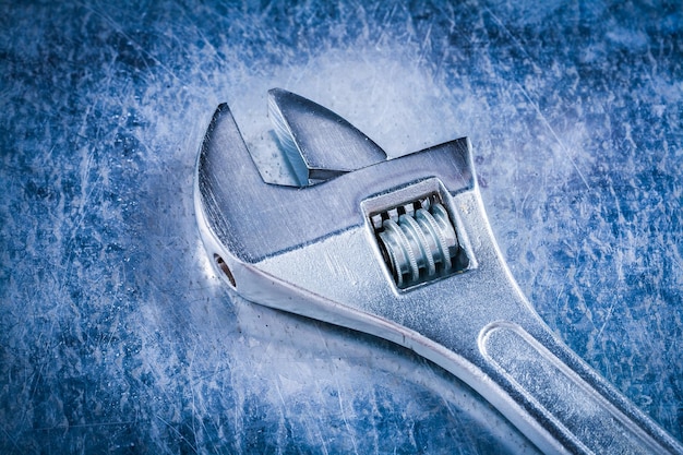 Stainless adjustable spanner on scratched metallic background construction concept