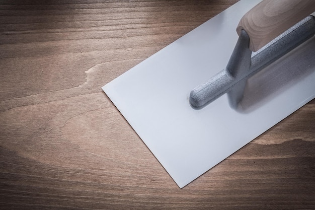 Stainless glazed plastering trowel on wooden board construction