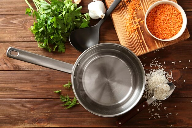 Photo stainless saucepan parsley and lentil on wooden background